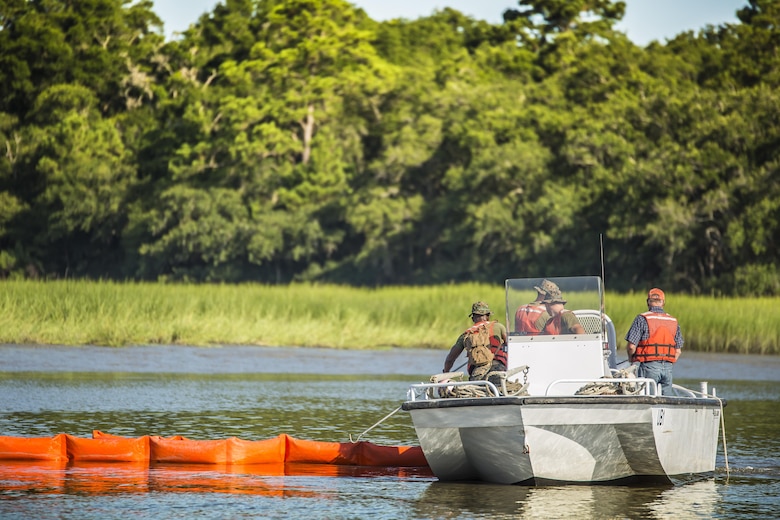 Marines and civilian personnel set a boom to contain a simulated oil spill aboard Marine Corps Air Station Beaufort July 13. The boom is towed behind the boats and acts as a large net, trapping the oil to be collected by a skimmer boat. Both Marines and civilians are part of the Facility Response Team for MCAS Beaufort and trained together to respond in case of a real spill. The Marines are with air station fuels and the civilians are with the Natural Resources Environmental Affairs Office.