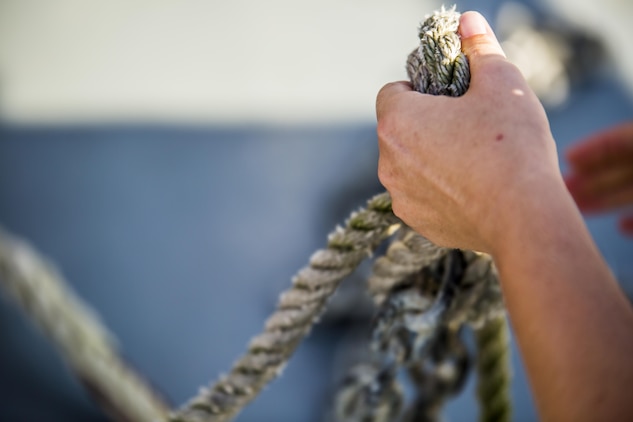 Marines attach an anchor to a boom during a simulated oil spill aboard Marine Corps Air Station Beaufort July 13. The boom is towed behind the boats and acts as a large net, trapping the oil to be collected by a skimmer boat. The Marines are with Aircraft Rescue and Firefighting.