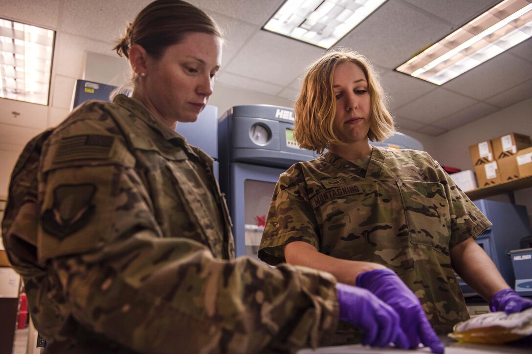 Air Force Staff Sgt. Megan Montagnino, right, verifies details of a blood packet with a medical technician in Craig Joint Theater Hospital at Bagram Airfield, Afghanistan, July 8, 2016. Montagnino, the noncommissioned officer in charge, is assigned to the Expeditionary Medical Group microbiology and the blood bank. Before the blood bank hands out any donation, technicians test the blood and systematically check to ensure patients receive the right blood for their needs. Air Force photo by Senior Airman Justyn M. Freeman     