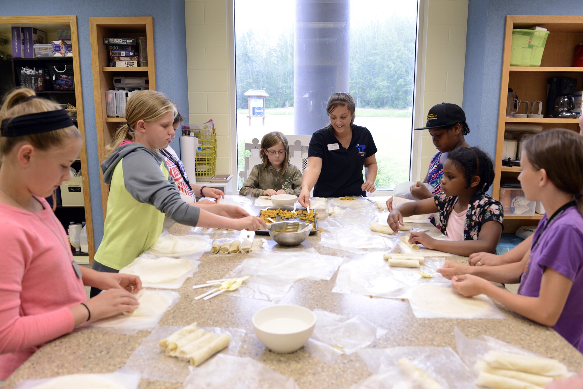 Megan Wilson, a child and youth program assistant at Two Rivers Youth Center, teaches a group of Joint Base Elmendorf Richardson aspiring chefs how to wrap egg rolls at the Two Rivers Cooking Camp hosted at JBER, Alaska, July 11, 2016. Cooking Camp participants learn kitchen safety and essential living skills, Wilson said. (U.S. Air Force photo by Airman 1st Class Javier Alvarez)