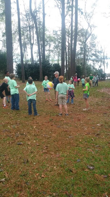 Volunteer Ron Morrissey leads a group of Sneads Elementary fourth graders in Beach Ball Q+A, a game that quizzes students on facts about frogs, at the Every Kid in a Park fieldtrip at Lake Seminole