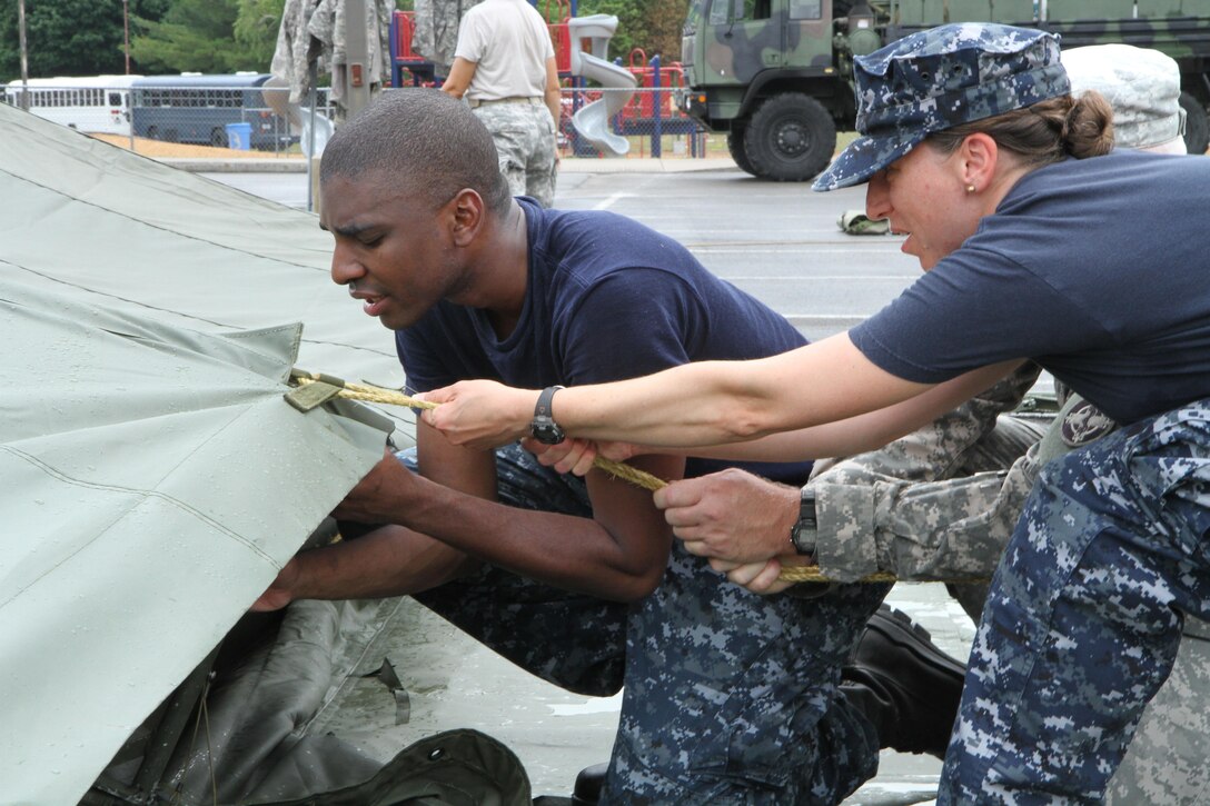 Service members from both the Army and the Navy help to set up tents for veterinary services during Healthy Cortland July 14, 2016. Healthy Cortland is one of the Innovative Readiness Training missions which provides real-world training in a joint civil-military environment while delivering world-class medical care to the people of Cortland, N.Y., from July 15-24.