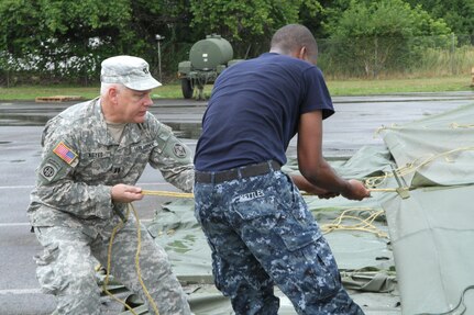 Service members from both the Army and the Navy help to set up tents for veterinary services during Healthy Cortland July 14, 2016. Healthy Cortland is one of the Innovative Readiness Training missions which provides real-world training in a joint civil-military environment while delivering world-class medical care to the people of Cortland, N.Y., from July 15-24.