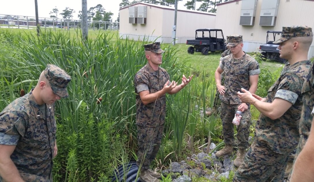 Gunnery Sergeant William Satterfield, center, an instructor with Combat Engineer Instruction Company; takes the students attached to Combat Engineer Officer course 7-16 (CEO 7-16) on a tour around Courthouse Bay Camp Lejeune, N.C. to illustrate how a drainage plan is built and discusses drainage considerations, July 11, 2016. Pictured from left to right are Second Lieutenant Gabriel Van Langevelde, Gunnery Sergeant William Satterfield, Second Lieutenants Jason Sander and Michael Hogan.
