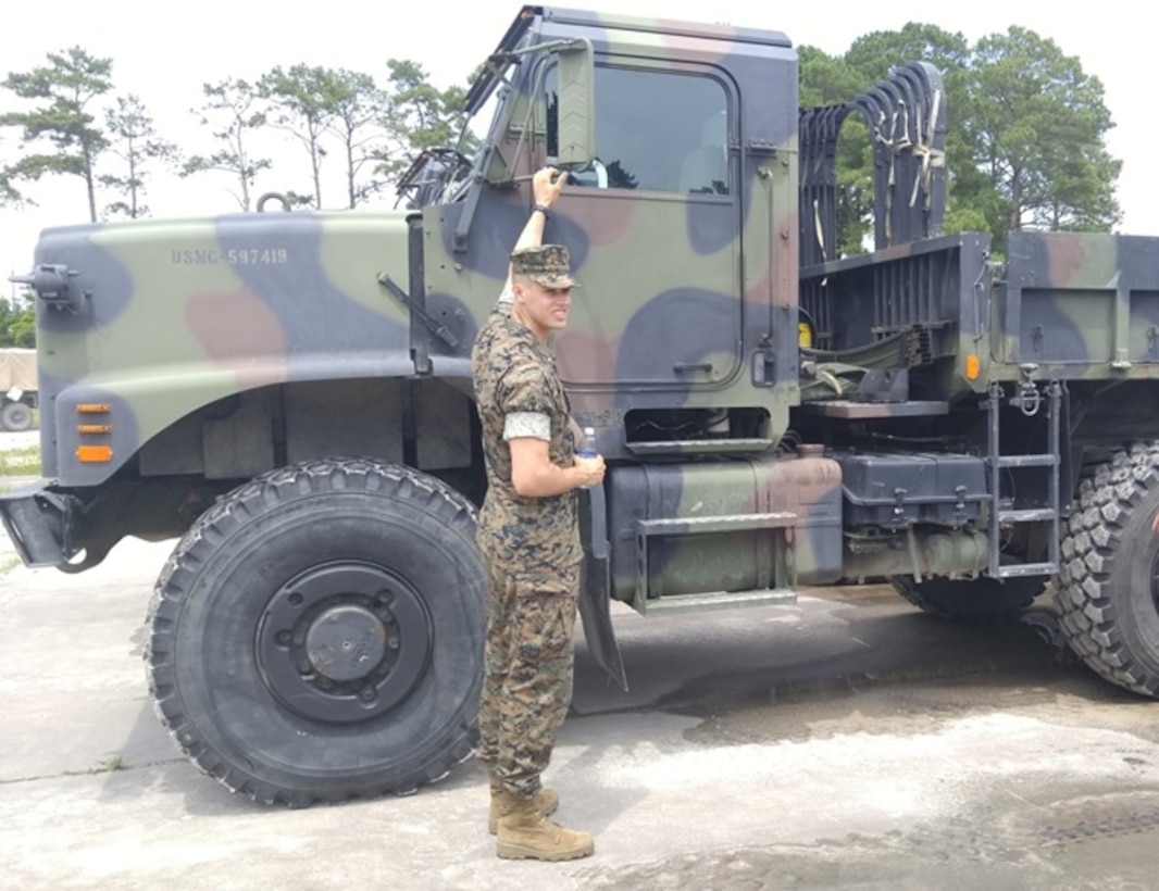 Second Lieutenant Jacob Cybulski, attached to Combat Engineer Officer course 7-16 (CEO 7-16), poses with a Medium Tactical Vehicle Replacement (MTVR) dump truck while on a tour of the Marine Corps Engineer School (MCES) motor transportation pool aboard Courthouse Bay, Camp Lejeune, N.C., July 11, 2016. The purpose of the tour was to teach the students of CEO 7-16 about the various heavy engineer equipment assets available. 