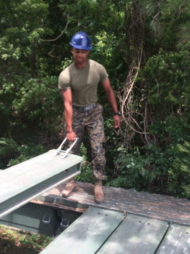 Second Lieutenant Aaron Graham, attached to Combat Engineer Officer course 5-16 (CEO 5-16), helps lift a decking component of the bridge to put it in place to help build a Medium Girder Bridge during a practical application, May 10, 2016 . Practical applications give the students hands on experience to better understand how to create these bridges. 