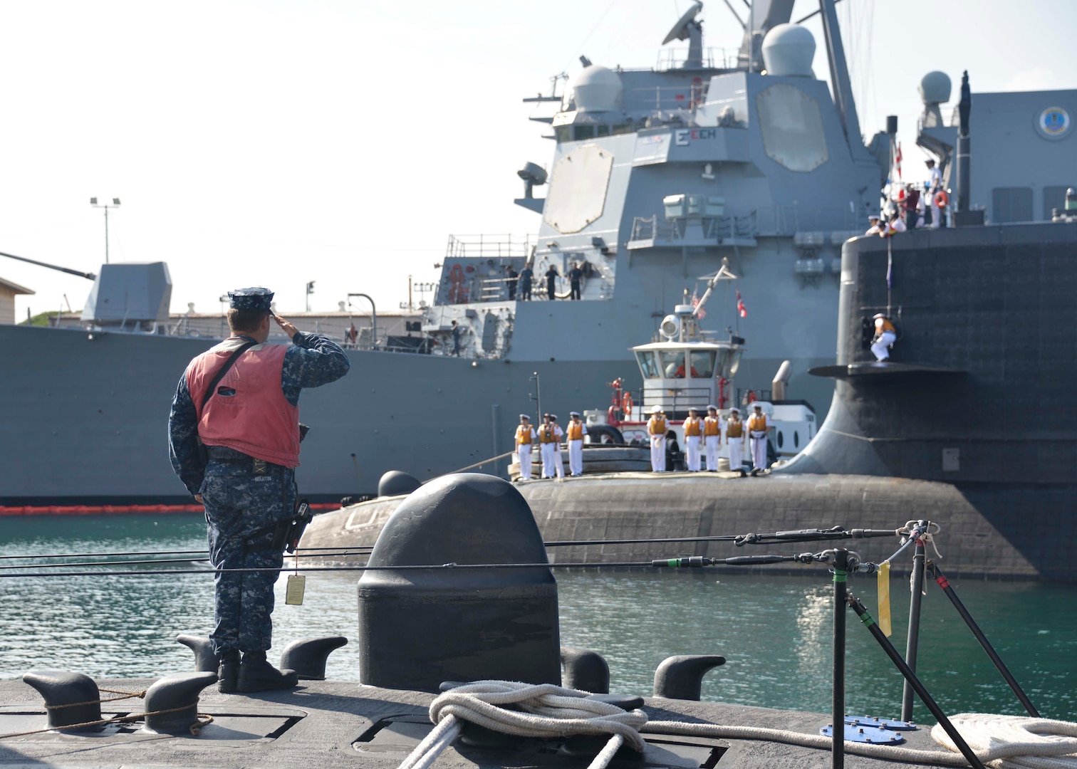 In this file photos, Machinist's Mate 3rd Class Joshua Martin, assigned to the Los Angeles-class attack submarine USS Buffalo (SSN 715), renders a passing salute to the Japan Maritime Self-Defense Force submarine JS Hakuryu (SS 503) as the submarine arrives at Joint Base Pearl Harbor-Hickam. While in port, the submarine's crew will conduct various training evolutions, continue to build positive relationships with the United States, and have the opportunity to enjoy the sights and culture of Hawaii.