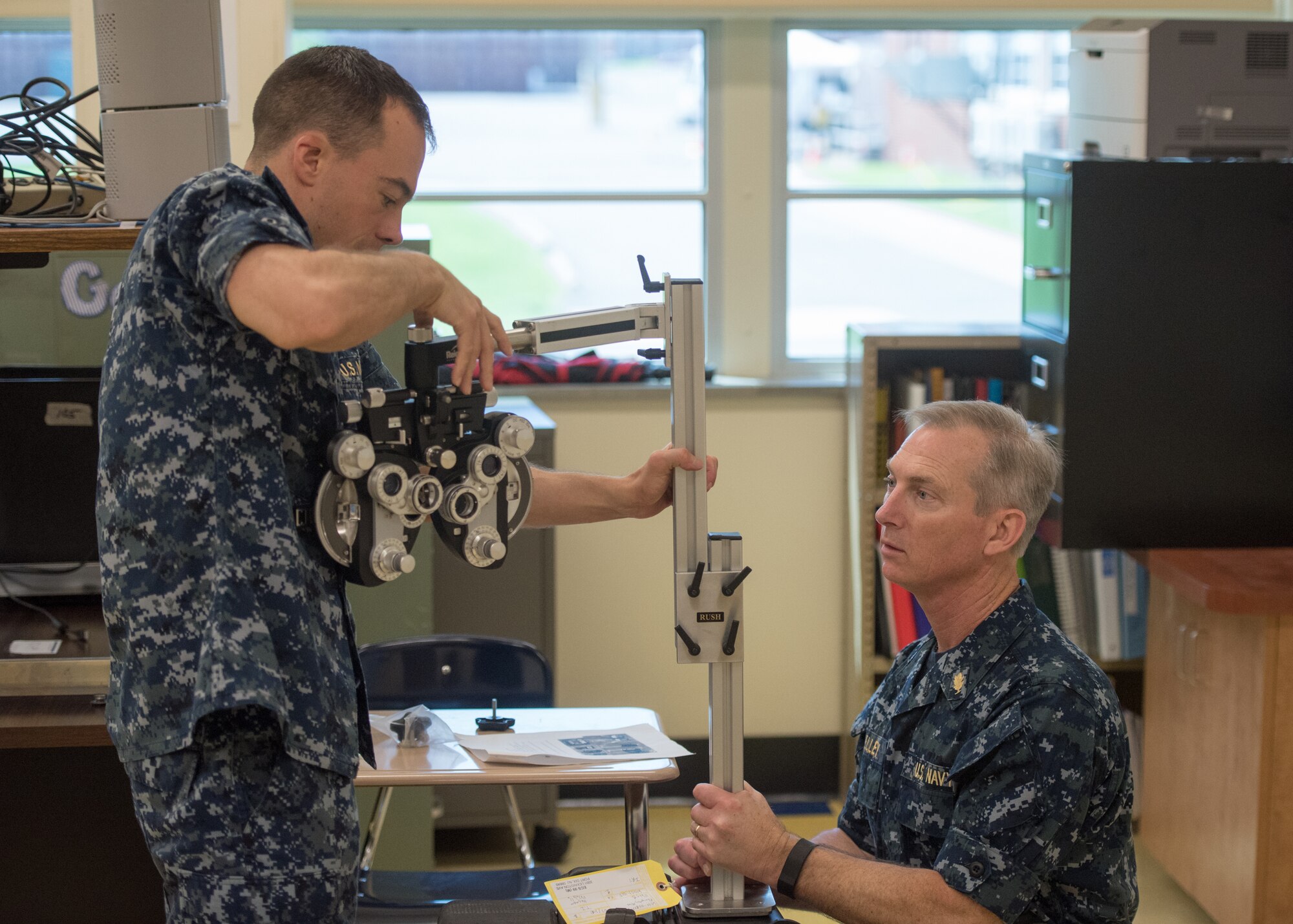 U.S. Navy Lt. Christopher Luft (left), an optometrist at Branch Health Clinic Navy Station Norfolk, and U.S. Navy Cmdr. Fred Kelley, an optometrist with Operational Health Support Unit Portsmouth Detachment M, setup optometry equipment at Paducah Tilghman High School in Paducah, Ky., July 17, 2016, in preparation for Bluegrass Medical Innovative Readiness Training. The program will offer medical and dental care at no cost to residents in three Western Kentucky locations from July 18 to 27.(U.S. Air National Guard photo by Master Sgt. Phil Speck)