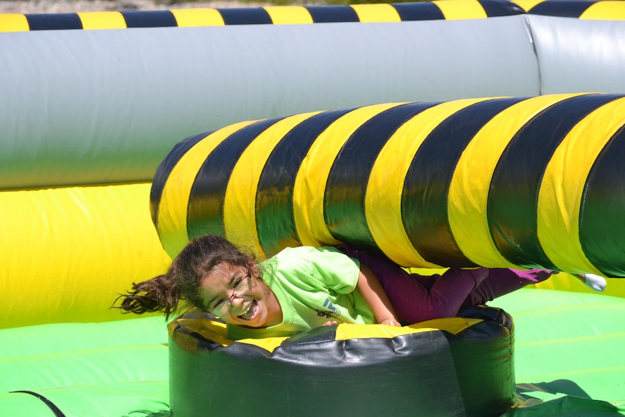 An inflatable obstacle rolls over Adrienne Sanchez during the Summer Slam Base Picnic at Schriever Air Force Base, Colorado, Friday, July 15, 2016. The obstacle course made participants jump or duck over spinning beams until all of the players were knocked off their platform. (U.S. Air Force photo/Brian Hagberg)