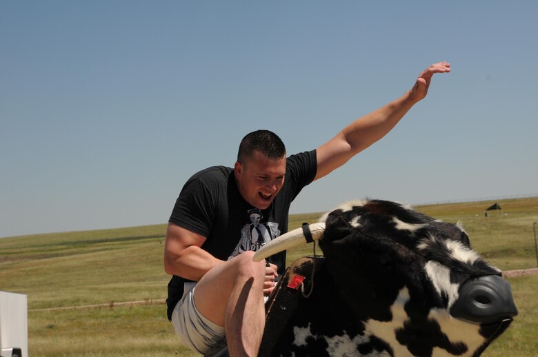 A rider tries to hang on to a mechanical bull during the Summer Slam Base Picnic at Schriever Air Force Base, Colorado, Friday, July 15, 2016. The mechanical bull was a new addition to the base picnic and created long lines of determined attendees to see who could ride the longest. (U.S. Air Force photo/Airman William Tracy)