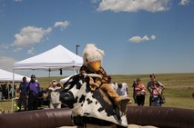 The Schriever griffin mounts a mechanical bull during the Summer Slam Base Picnic at Schriever Air Force Base, Colorado, Friday, July 15, 2016. The griffin was one of the many riders waiting to go for eight seconds. (U.S. Air Force photo/Airman William Tracy)