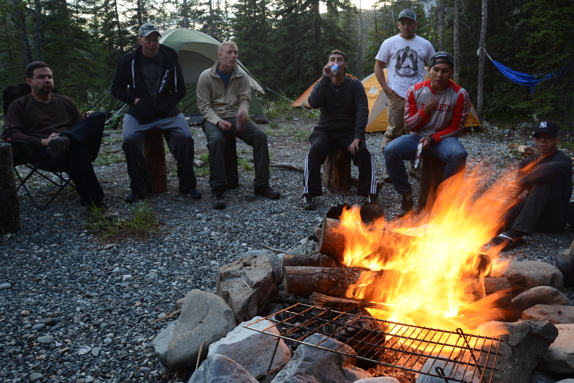 Participants of a chaplain-sponsored camping trip relax by the campfire near Lion’s Head, Alaska, July 9, 2016. The campground had a fire pit and logs to sit on for a peaceful place to eat and talk. The Joint Base Elmendorf-Richardson chaplain community hosted the whitewater rafting and camping trip for single service members and other Department of Defense partners. (U.S. Air Force photo by Airman 1st Class Christopher R. Morales)
