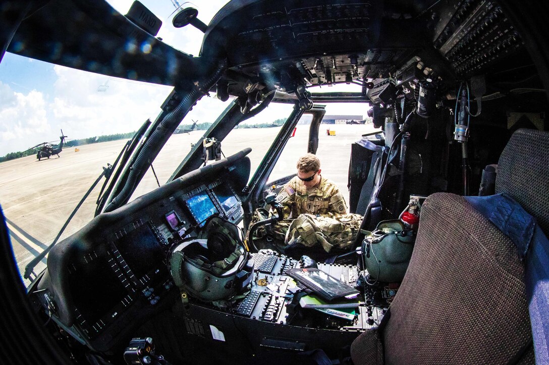 Army Capt. Daniel Prial prepares his gear inside a UH-60 Black Hawk helicopter before participating in a routine flight over Fort Bragg, N.C., July 12, 2016. Prial is a pilot assigned to the 3rd General Support Aviation Battalion. Army photo by Capt. Adan Cazarez