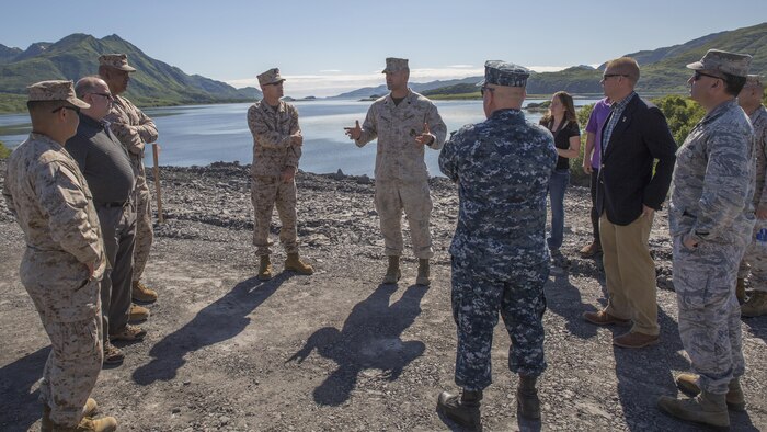 Gunnery Sgt. Brandon Watson (center), project coordinator for Innovative Readiness Training Old Harbor, Alaska, briefs a group of distinguished visitors from different military branches and civilian agencies July 11, 2016. IRT Old Harbor is part of a civil and joint military program to improve military readiness while simultaneously providing quality services to underserved communities throughout the United States.