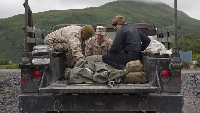 Petty Officer 3rd Class Jerry S. Pring (left), a hospital corpsman with Detachment B, Marine Wing Support Squadron-472, Marine Aircraft Group 49, 4th Marine Aircraft Wing, Marine Forces Reserve, Lance Cpl. David J. Rowe (center), an aircraft rescue and firefighting specialist with Det. B, MWSS-472, and Lance Cpl. Benjamin A. Bakker (right), an automotive maintenance technician with Engineer Support Company, 6th Engineer Support Battalion, 4th Marine Logistics Group, simulate a casualty evacuation at Innovative Readiness Training Old Harbor, Alaska, July 9, 2016. IRT Old Harbor is part of a civil and joint military program to improve military readiness while simultaneously providing quality services to underserved communities throughout the United States.