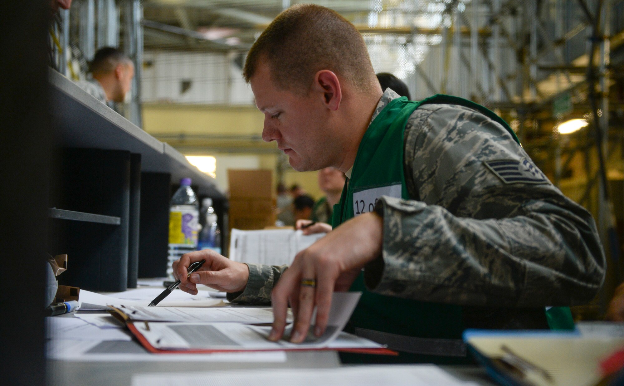 U.S. Air Force Staff Sgt. Daniel McMillan, 100th Force Support Squadron customer support NCO in charge, looks through a deployment folder in the personnel deployment function line during an exercise July 14, 2016, on RAF Mildenhall, England. Deployment folders are inspected to ensure individuals have completed the necessary training and have all the required documentation needed for their deployment. (U.S. Air Force photo by Staff Sgt. Micaiah Anthony)