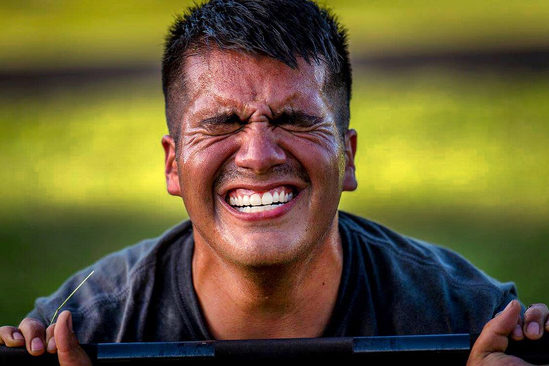 Air Force Tech. Sgt. David Alderete grits his teeth as he does barbell squats during the Fourth Annual Spc. Hilda I. Clayton Best Combat Camera Competition at Fort Meade, Md., July 11, 2016. Alderete is assigned to the 1st Combat Camera Squadron. Air Force photo by Staff Sgt. Kenneth W. Norman 