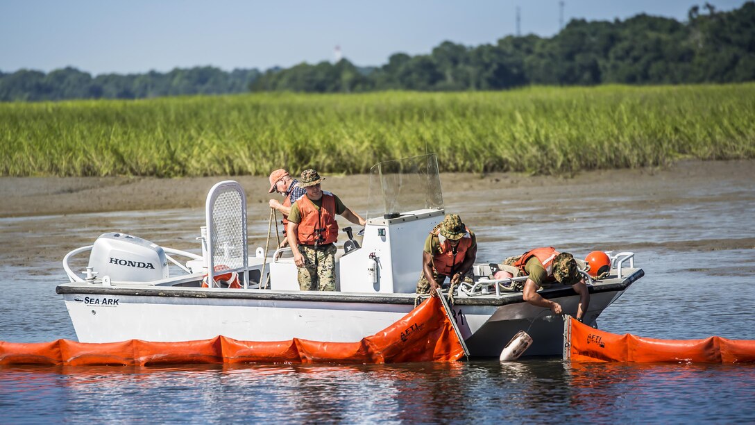 Marines and civilian personnel use a boom to contain a simulated oil spill at Marine Corps Air Station Beaufort, South Carolina, July 13, 2016. The boom is towed behind the boats and acts as a large net, trapping the oil to be collected by a skimmer boat. The Marines are with the air station fuels section and the civilians are with the Natural Resources Environmental Affairs Office.