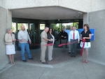 Navy Capt. Richard McCarthy, Defense Contract Management Agency San Diego commander, cuts the ribbon for the office's new facility. Three of the longest serving office employees — Jane Morales, Gabriel Tapia and Rachelle Munz — held the ribbon in celebration of their 75 combined years at the previous facility.