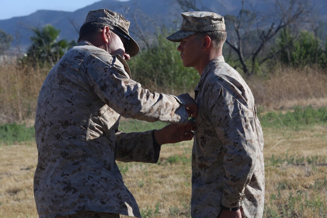 Chief Warrant Officer 5 Vincent Kyzer, the 1st Marine Division Gunner, pins the Navy and Marine Corps Achievement Medal on Lance Cpl. Chance Goff, a rifleman with Company C, 1st Battalion, 7th Marine Regiment, for earning the highest overall score in the infantry marksmanship competition during the 2016 1st Marine Division Infantry Squad Competition award ceremony at Camp Pendleton, Calif., July 14, 2016. The 1st Marine Division hosted its annual Infantry Squad or “Super Squad” competition which pits the 1st, 5th, and 7th Marine Regiments and a Light Armored Reconnaissance Battalion against each other in tests designed to evaluate their leadership and small unit, infantry skills. (U.S. Marine Corps photo by Lance Cpl. Shellie Hall)