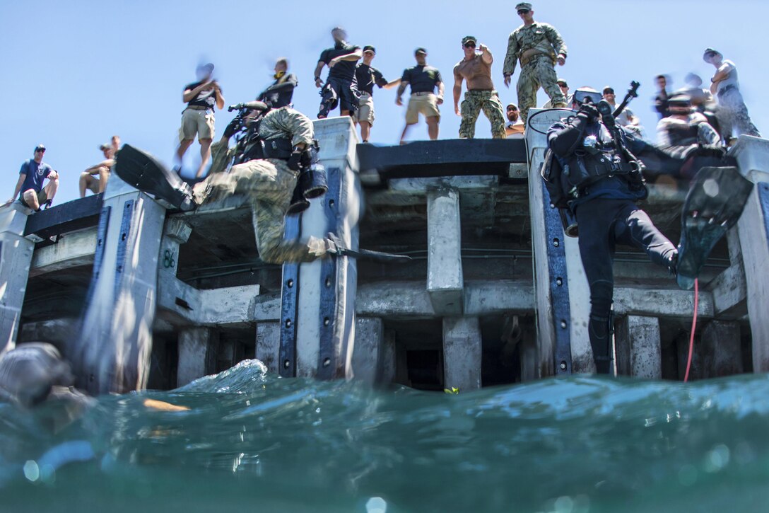 Army Pfc. Aaron Gaugler and Coast Guard Diver 2nd Class Kendall Smith enter the water as part of a pier maintenance training-mission led by Navy Underwater Construction Team 2 during Rim of the Pacific 2016 at Joint Base Pearl Harbor-Hickam, Hawaii, July 12, 2016. The maritime exercise involves about 25,000 participants from 26 nations, 49 ships, six submarines and about 200 aircraft. Navy photo by Petty Officer 1st Class Charles E. White