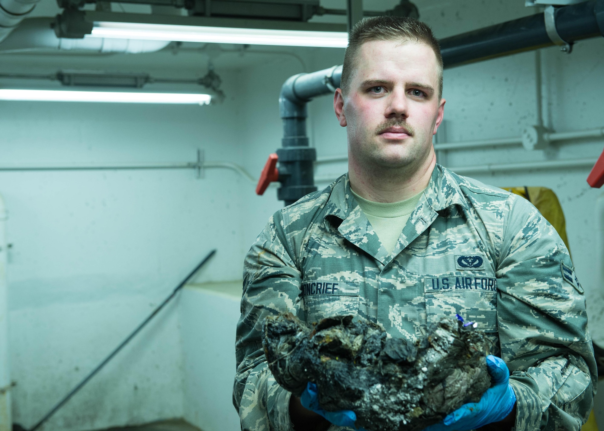 U.S. Air Force Airman 1st Class Troy Moncrief, a 354th Civil Engineering Squadron wastewater apprentice, displays solids removed from sewage after he removed it from a trap underground at the Eielson Air Force Base, Alaska, wastewater treatment plant July 14, 2016. Anything that cant be treated by aeration, bacteria or chemicals is removed prior to entering settling tanks and ponds. (U.S. Air Force photo by Staff Sgt. Shawn Nickel)
