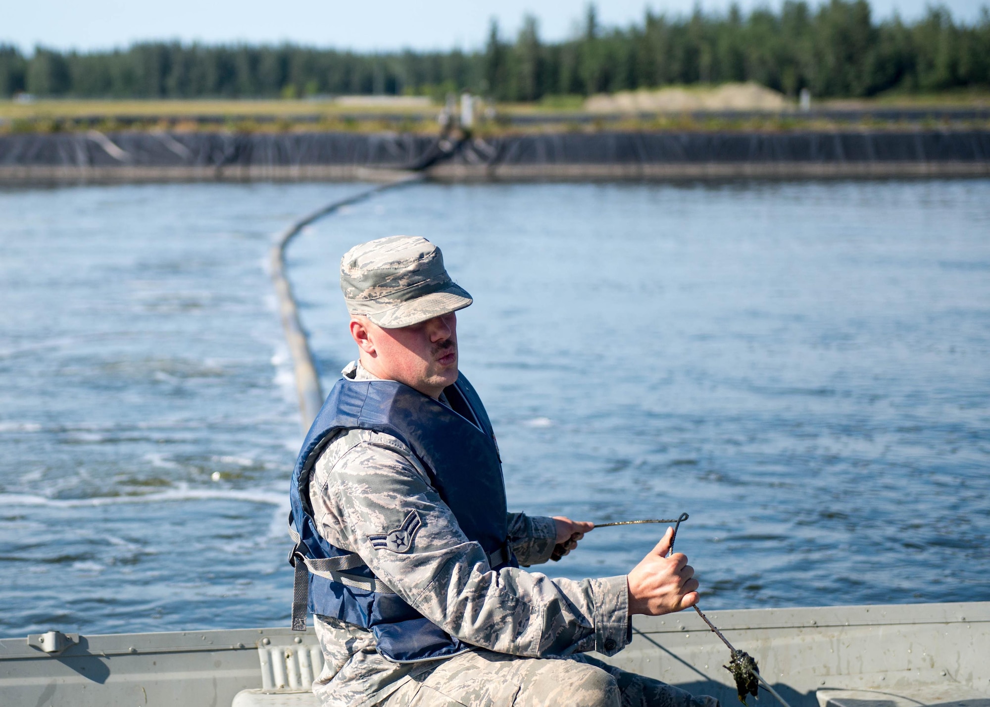 U.S. Air Force Airman 1st Class Troy Moncrief, a 354th Civil Engineering Squadron wastewater apprentice, uses a boat to inspect aeration equipment in ponds at the Eielson Air Force Base, Alaska, wastewater treatment plant July 15, 2016. The manufactured holding pond lined with thick black plastic hold millions of gallons of waste that is treated in a week’s time after it enters the plant. (U.S. Air Force photo by Staff Sgt. Shawn Nickel)
