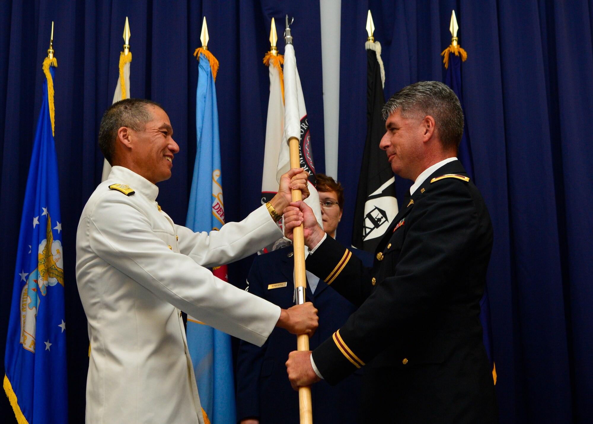 Army Col. Louis Finelli receives the Armed Forces Medical Examiner System guidon from Navy Rear Adm. Colin Chinn, Defense Health Agency director of research, development and acquisition, during a Change of Directorship Ceremony July 18, 2016, at the Landings on Dover Air Force Base, Del. Passing of a unit’s guidon symbolizes the passing of directorship from one officer to the next. (U.S. Air Force photo/Senior Airman William Johnson)