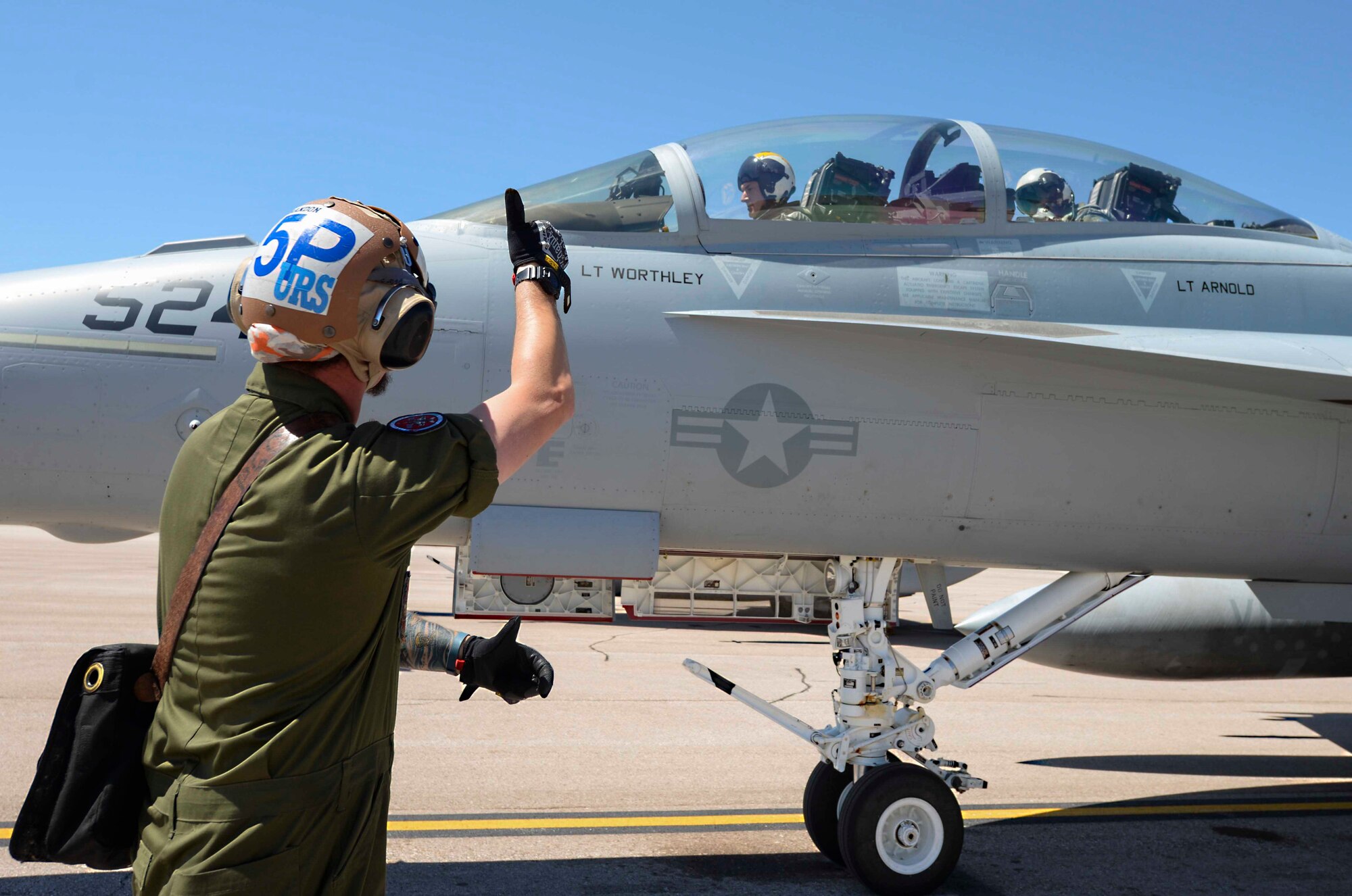 Contractor John Frohlich, a plane captain assigned to the Electronic Attack Squadron (VAQ) 129, communicates with Navy EA-18G Growler Pilot Lt. Eric Holler, to start a jet engine before a training flight at Ellsworth Air Force Base, S.D., July 15, 2016. Plane captains are in charge of inspecting aircraft as well as being the main mechanics to service the jets if an error occurs. (U.S. Air Force photo by Airman 1st Class Sadie Colbert/Released)