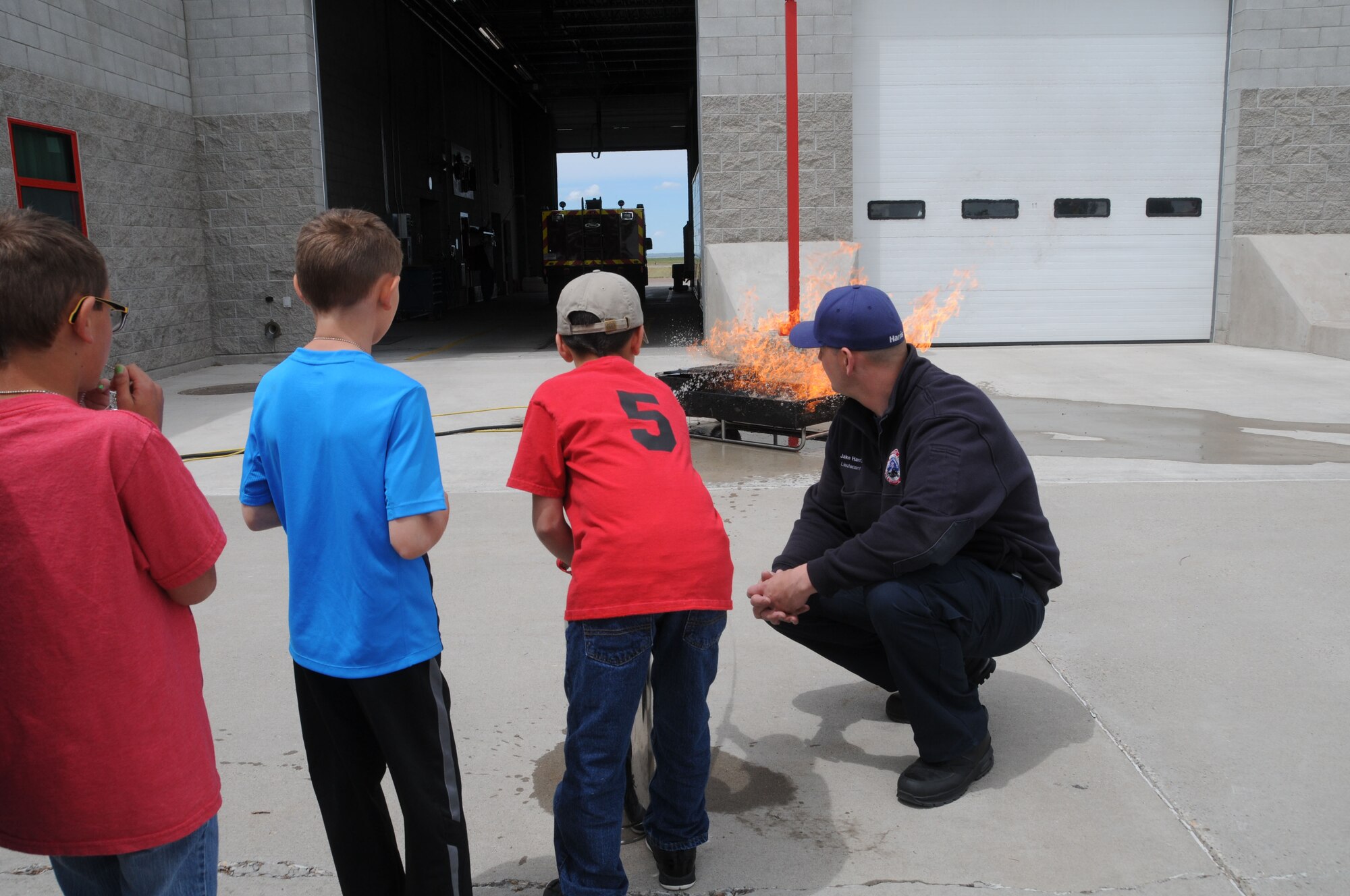 Montana Air National Guard Fire Department Lt. Jacob Harris observes as a child uses a fire extinguisher on a fire during a STARBASE tour of the station June 15, 2016. (U.S. Air National Guard photo/Senior Master Sgt. Eric Peterson)