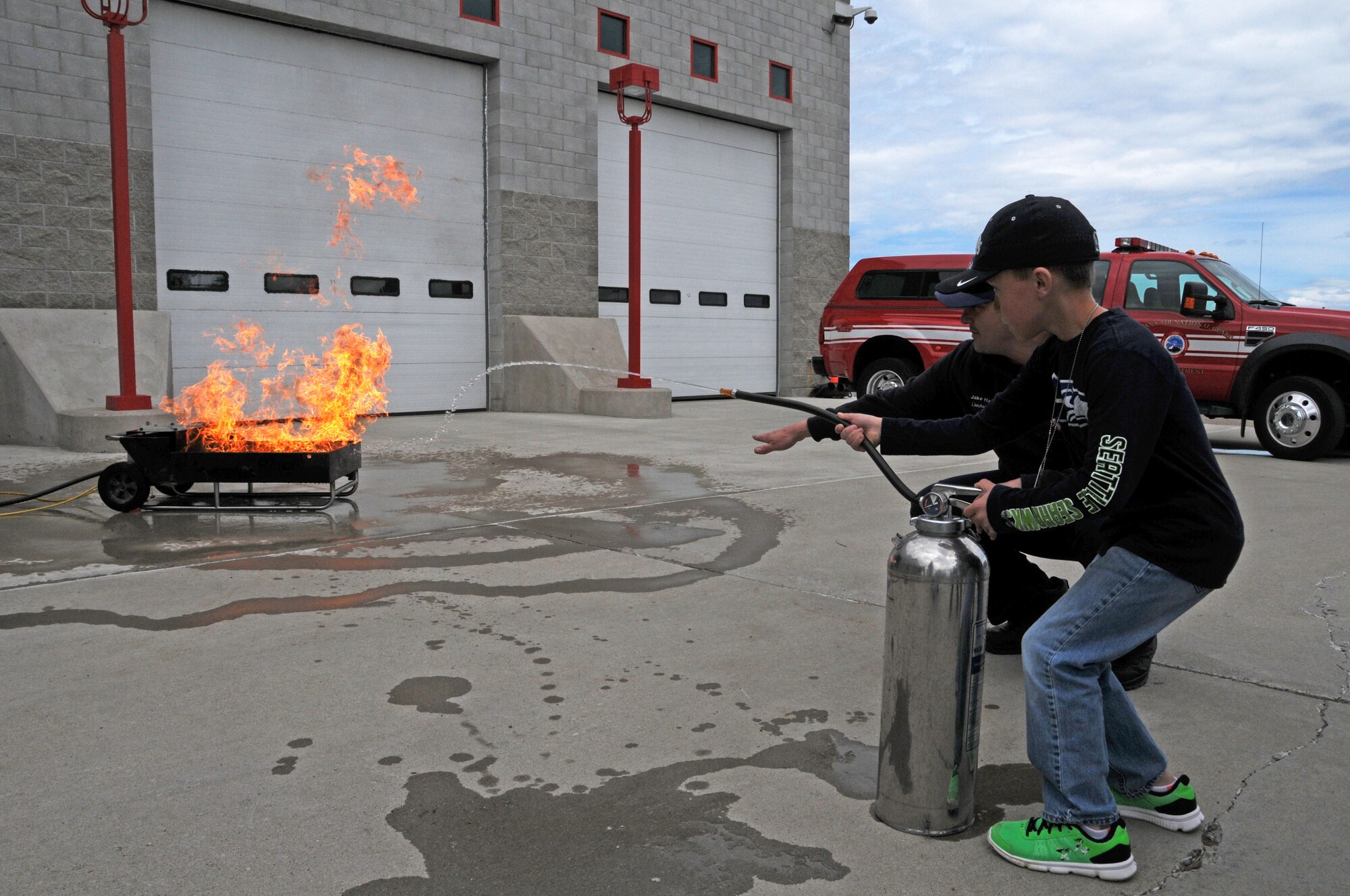 Montana Air National Guard Fire Department Lt. Jacob Harris shows a child how to operate a fire extinguisher on a fire during a STARBASE tour of the station June 15, 2016. (U.S. Air National Guard photo/Senior Master Sgt. Eric Peterson)