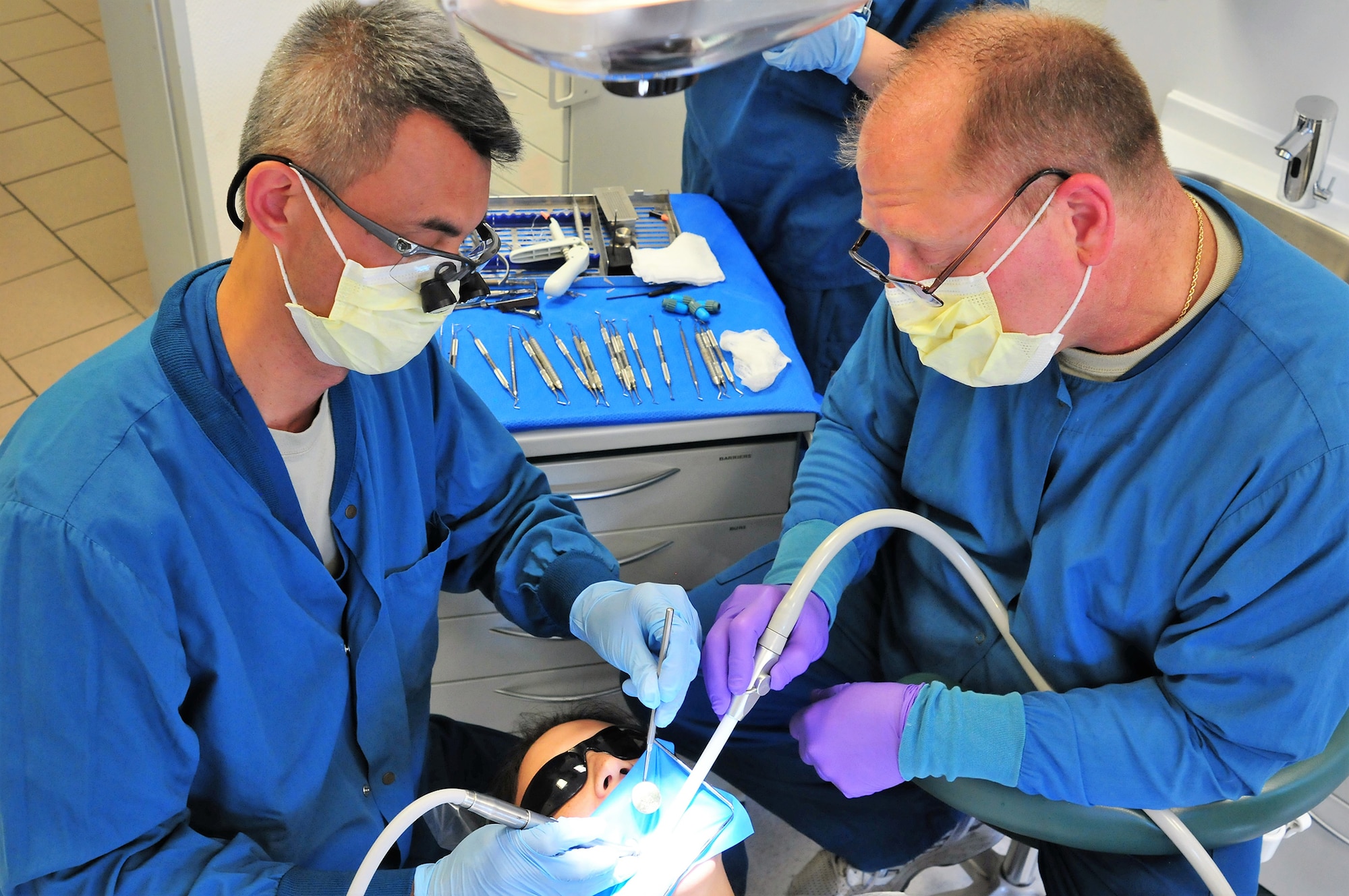 Lt. Col. Simon Nguyen, a dentist with the 178th Wing, and Tech. Sgt. Darryl Chaplin, a dental assistant with the 178th Wing, fill cavities at Ramstein Air Base in Germany, July 18, 2016. Several members of the Ohio Air National Guard temporarily deployed to Ramstein Air Base to provide assistance and to receive training in medical, communications and logistics squadrons. (Ohio Air National Guard photo by Airman 1st Class Rachel Simones)