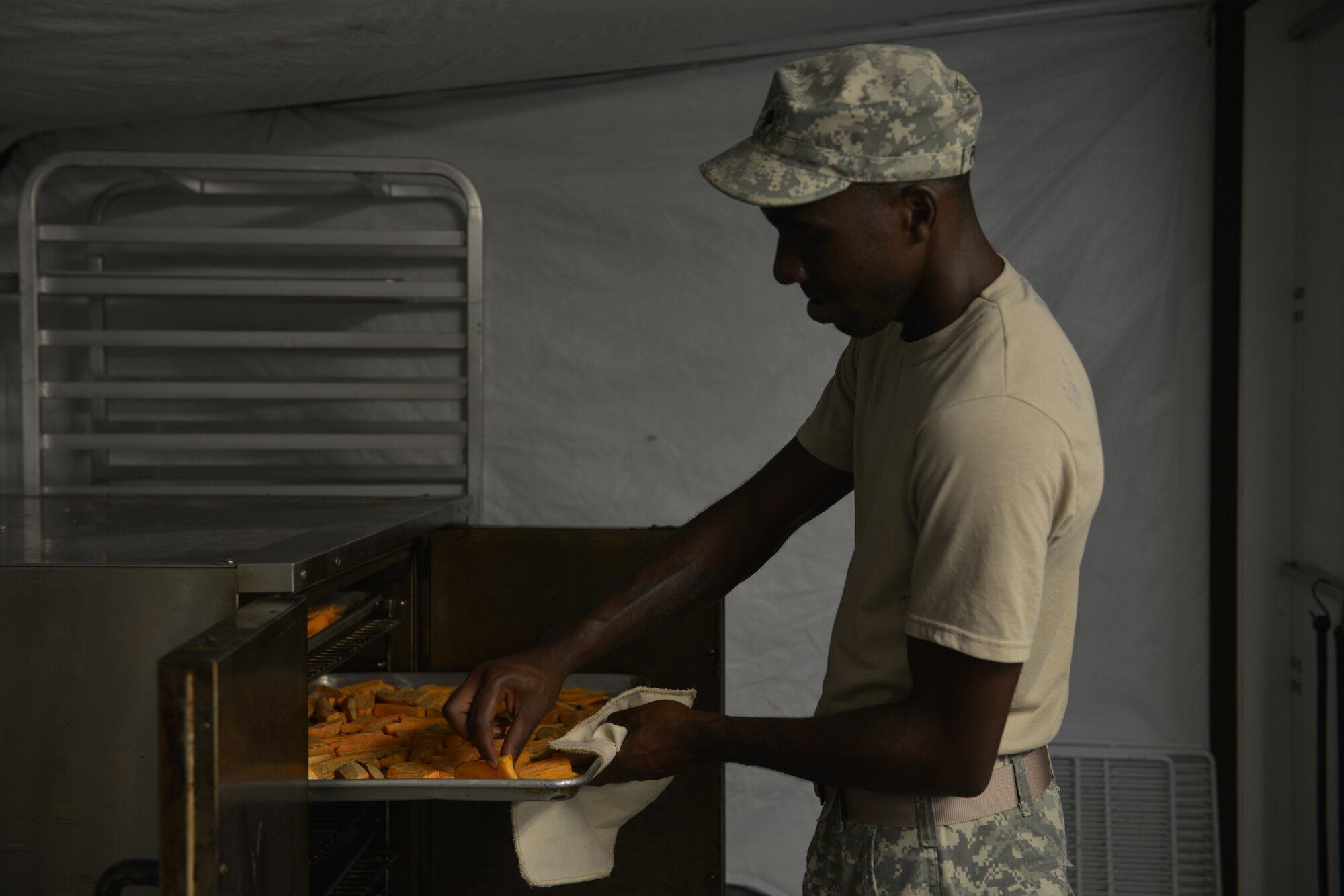 U.S. Army Spc. David Palmer, Echo Company, 5th Battalion, 159th General Support Aviation Brigade cook, checks the tenderness of sweet potato wedges during a training meal for the Philip A. Connely Culinary Field Competition at Fort Eustis, Va., July 13, 2016. The Army wide food service competition aims to improve the professionalism of food service personnel as a means to provide high quality meals to Soldiers in the field. (U.S. Air Force photo by Staff Sgt. Natasha Stannard)
