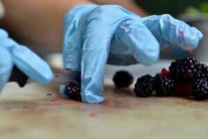 A U.S. Army Reserve Soldier assigned to the Echo Company, 5th Battalion, 159th General Support Aviation Brigade, slices blackberries for a cake topping at Fort Eustis, Va., July 13, 2016. The company was preparing the cake, along with other dishes, as a part of a practice run for the Philip A. Connely Culinary Competition. (U.S. Air Force photo by Staff Sgt. Natasha Stannard)