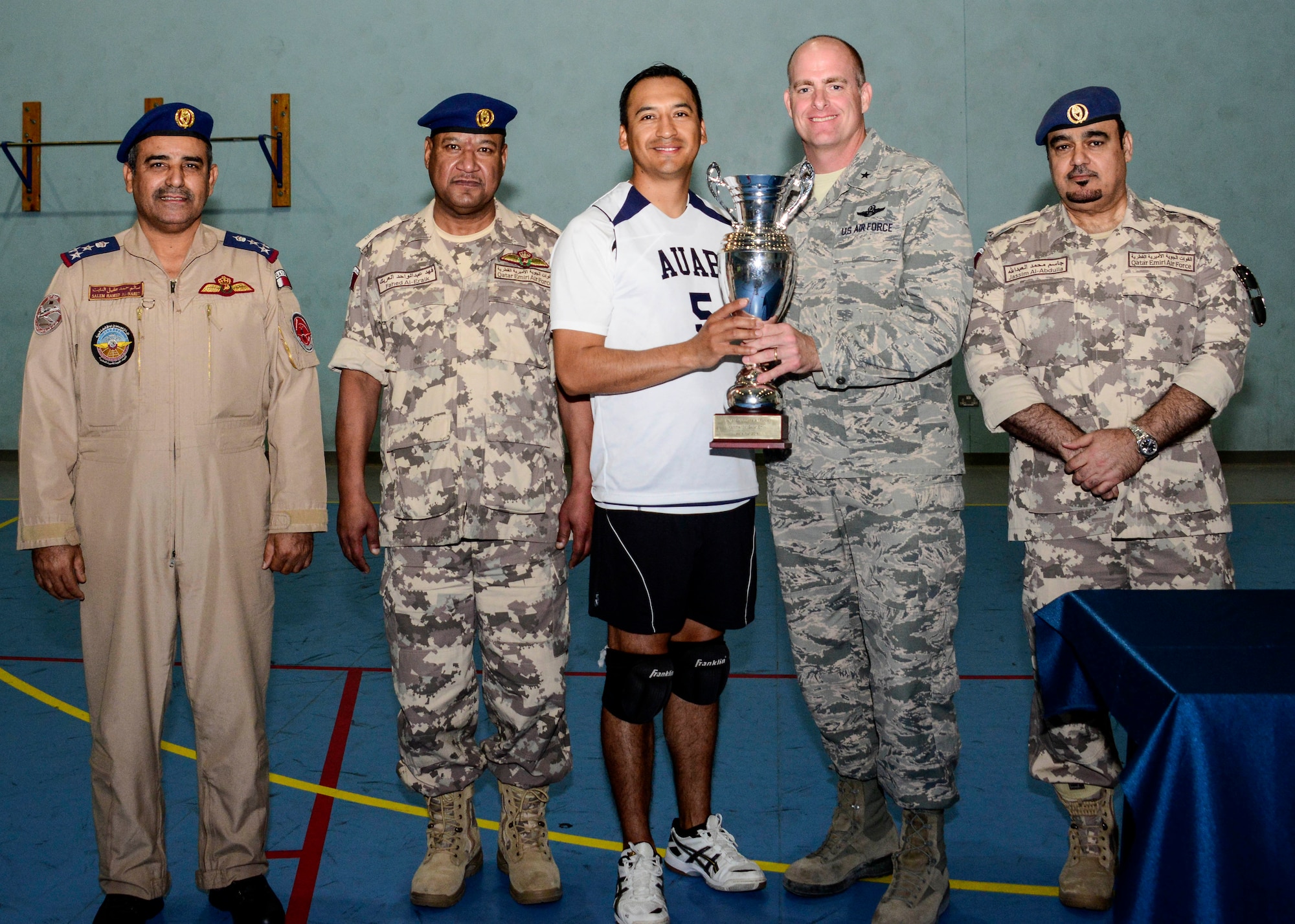 Brig. Gen. Darren James, 379th Air Expeditionary Wing commander, along with Qatar Emiri Air Force leadership present the championship trophy to Staff Sgt. William Sanchez, volleyball team captain, for winning the volleyball tournament hosted by the QEAF June 2, 2016, at Al Udeid Air Base, Qatar. The QEAF hosted the volleyball tournament as a means of having fun while strengthening and building the partnership and friendship between the service members. (U.S. Air Force photo/Senior Airman Janelle Patiño/Released)