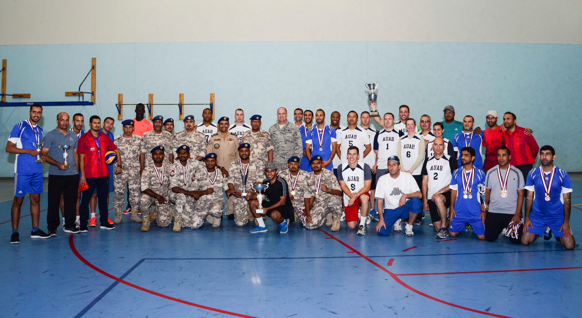 Members of Al Udeid Air Base and Qatar Emiri Air Force pose for a photo after a volleyball tournament June 7, 2016, at Al Udeid Air Base, Qatar. The QEAF hosted the game to bolster the partnership and build friendships between the U.S. and Qatari military. The U.S. team took first place at the tournament. (U.S. Air Force photo/Senior Airman Janelle Patiño/Released)