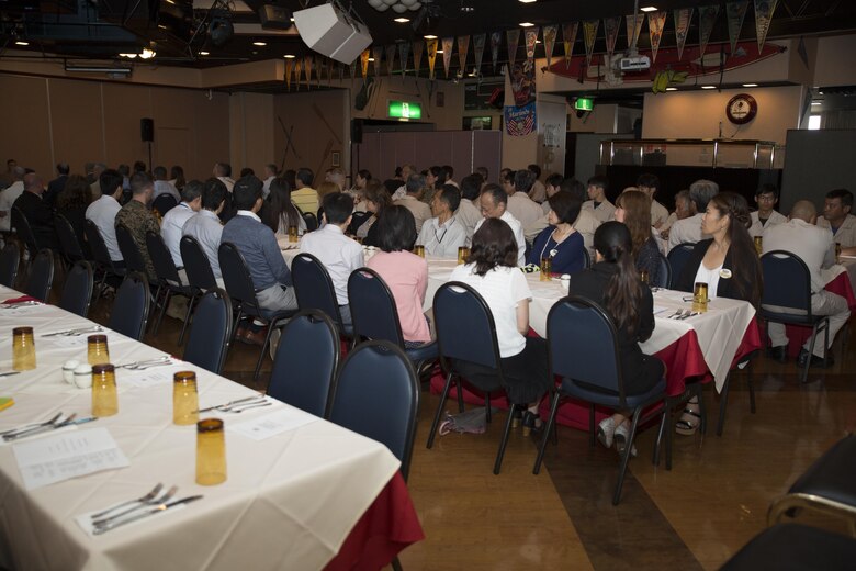 Guests attend a retirement ceremony at the Landing Zone inside Club Iwakuni at Marine Corps Air Station Iwakuni, Japan, and listen as U.S. Marine Corps Col. Robert V. Boucher, station commanding officer, gives a speech July 15, 2016. The ceremony acknowledged the appreciation for the retirees’ hard work and dedication toward the installation’s success over the years.  (U.S. Marine Corps photo by Lance Cpl. Joseph Abrego)
