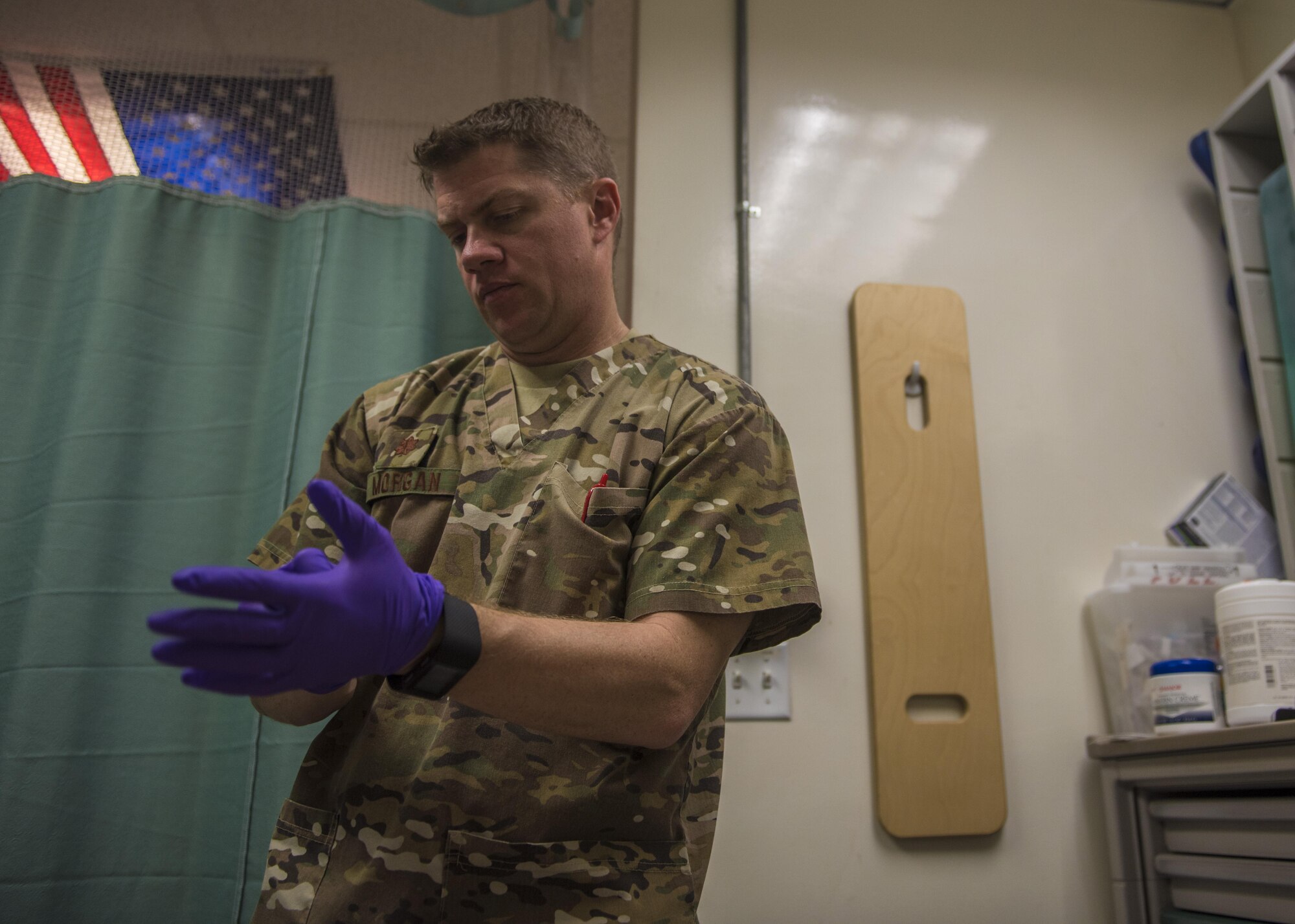 Maj. Brandon Morgan, 455th Expeditionary Medical Group physical therapist, puts on gloves, Bagram, Afghanistan, July 19, 2016. Morgan provides both in and out-patient treatment, which includes patients assigned to Bagram and local nationals. (U.S. Air Force photo by Senior Airman Justyn M. Freeman)