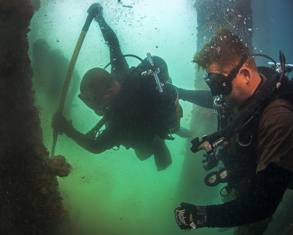 U.S. and Australian divers use a bar to remove marine growth from a pile during pier maintenance training led by Navy Underwater Construction Team 2 as part of Rim of the Pacific 2016 at Joint Base Pearl Harbor-Hickam, Hawaii, July 12, 2016. Navy photo by Petty Officer 1st Class Charles E. White