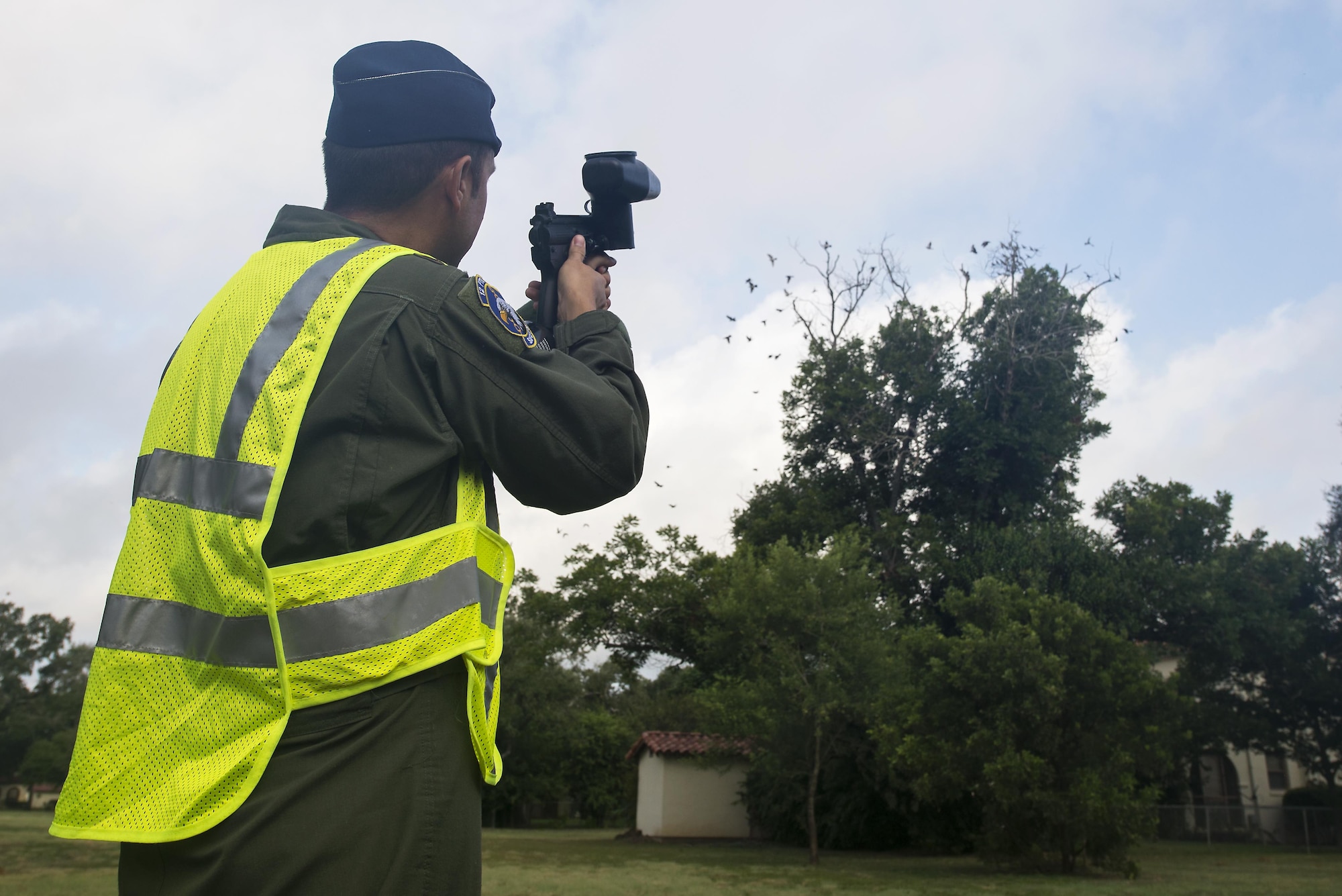 Maj. Will Rose, 12th Flying Training Wing Bird/Wildlife Aircraft Strike Hazard Program manager and T-6A Texan II flight safety officer, fires a paintball gun into a tree full of birds to scare them away July 13, 2016 at Joint Base San Antonio-Randolph. BASH Program team members use bangers, screamers and cracker shells, which are various types of pyrotechnics, to scare birds and wildlife away from where aircraft are taking off and landing.  