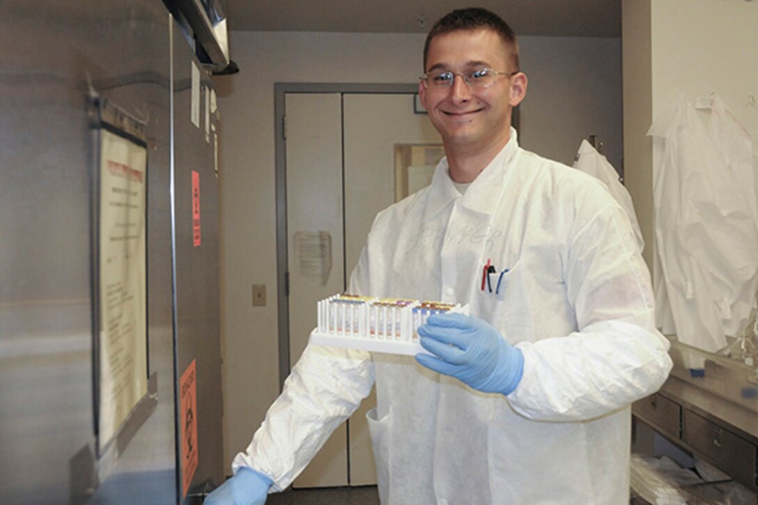 Army Spc. Chris Springer flashes a smile as he puts some of his lab-testing equipment into one of the many refrigerators at the Walter Reed Army Institute of Research’s Pilot Bioproduction facility. DoD photo by Katie Lange