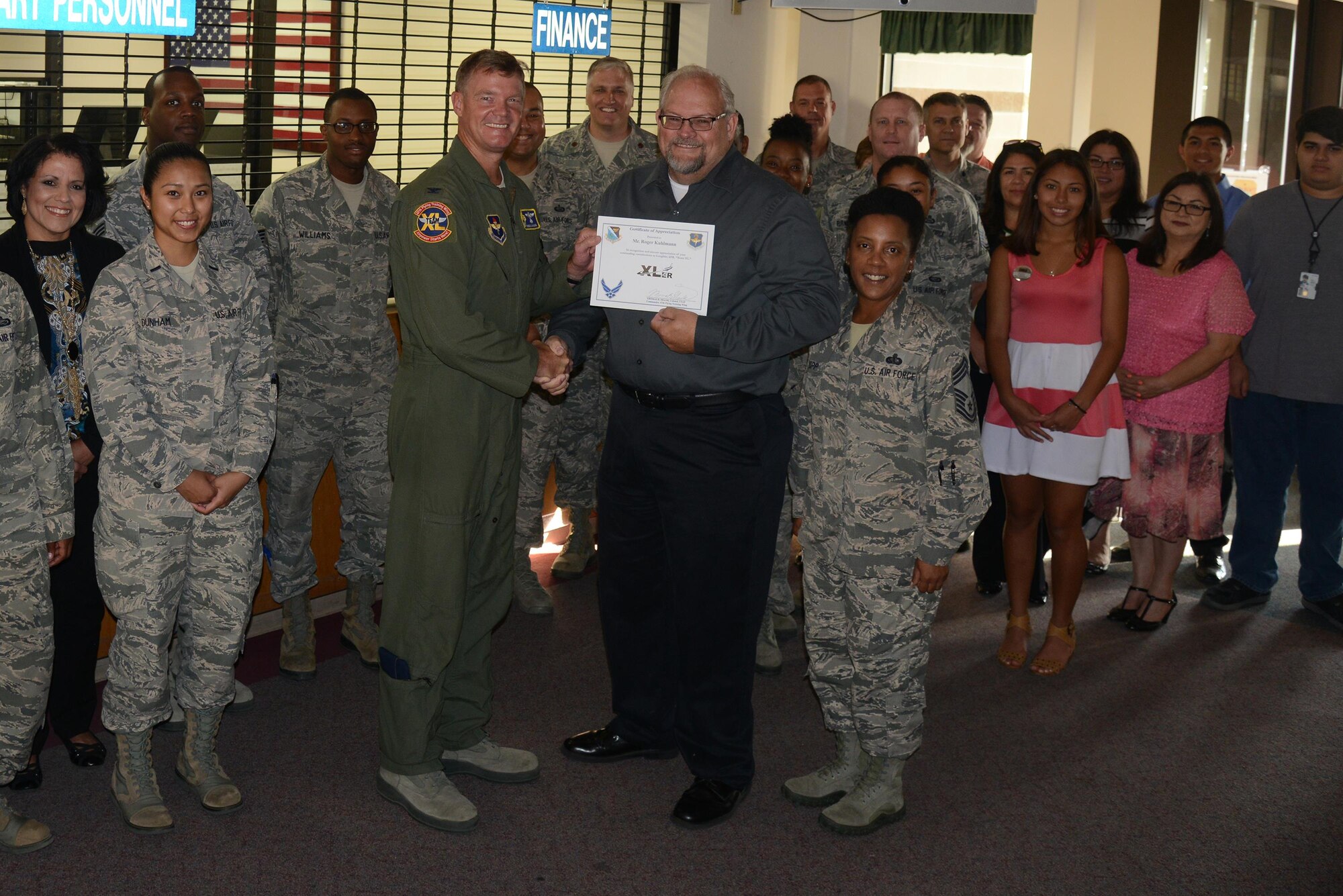 Roger Kuhlmann, 47th Force Support Squadron military and manpower flight chief, accepts the “XLer of the Week” award from Col. Thomas Shank, left, 47th Flying Training Wing commander, and Chief Master Sgt. Erica Shipp, 47th Mission Support Group superintendent, here, July 13, 2016. The XLer is a weekly award chosen by wing leadership and is presented to those who consistently make outstanding contributions to their unit and Laughlin. (U.S. Air Force photo/Airman 1st Class Brandon May)