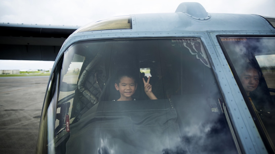 An Okinawa elementary student poses for a photo while exploring an MV-22 Osprey July 18 during a tour of Marine Corps Air Station Futenma, Okinawa, Japan. The tour strengthened the bilateral relationship between Marines and Okinawa residents by allowing them to see what Marines do on a daily basis and their day-to-day responsibilities in the workplace. During the visit, guests enjoyed a meal at the Habu Pit, toured the mess hall and explored various static displays on the flight line.