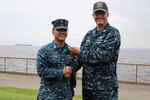 DLA Distribution Yokosuka, Japan, commander Navy Cmdr. Brian Johnson, right, promotes Christopher Ballesteros to the rank of Petty Officer 2nd Class as part of the Navy’s Meritorious Advancement Program.