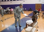 Senior Master Sgt. Helen Crouch, 174th Medical Group medical technician, gives medical history paperwork to a patient at the Greater Chenango Cares Innovative Readiness Training mission July 20, 2016, Norwich, N.Y. Before the patients are taken to dental, medical, or optometry, they are initially in-processed by medical technicians, gathering their height, weight, history, and vitals information. 