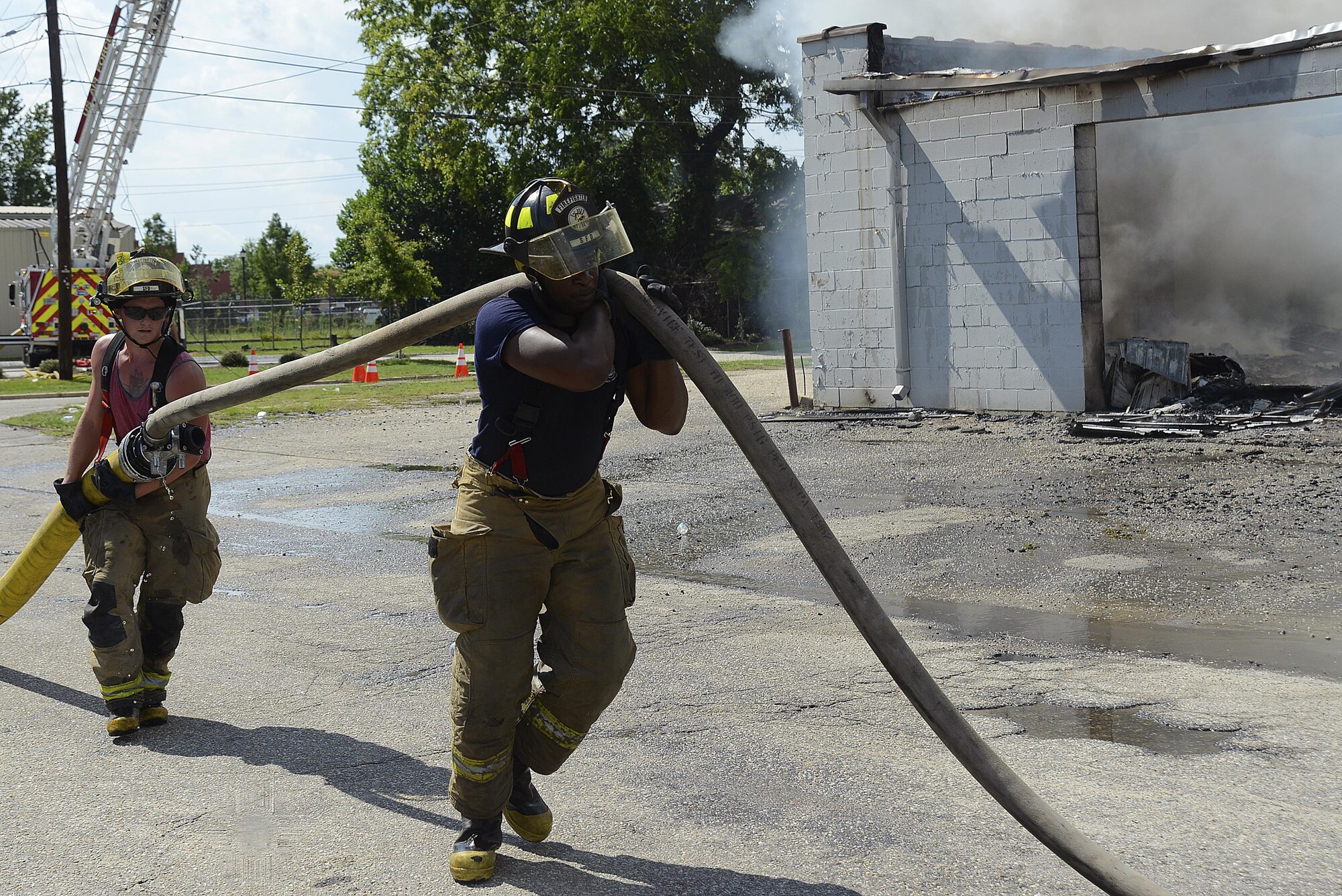 Two Sumter Fire Department firefighters work together to pull a hose closer to a fire in Sumter S.C., July 18, 2016. Sumter relies on Team Shaw during bigger disasters for additional manpower and resources. (U.S. Air Force photo by Airman BrieAnna Stillman)