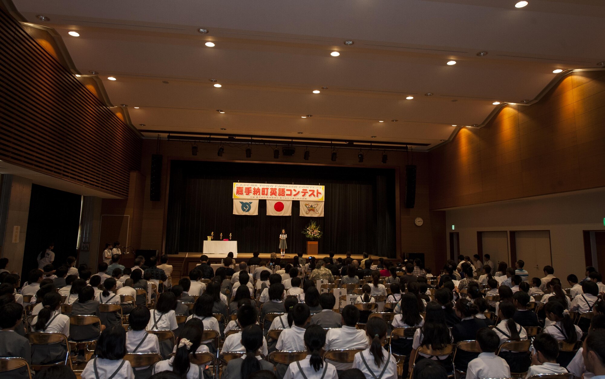 Audience members observe a local Okinawan student’s performance during the 19th annual Kadena Language Institute English Contest July 14, 2016, at Kadena Rotary Town Plaza, Okinawa, Japan. Contestants were from Yara Elementary School, Kadena Elementary School and Kadena Junior High School. (U.S. Air Force photo by Airman 1st Class Lynette M. Rolen)