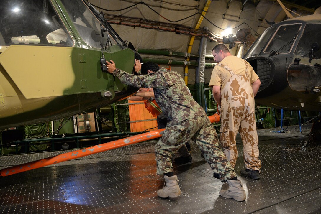 A member of the Afghan air force helps a crew member of an AN-124 to push a Mi-17 helicopter into place July 18, 2016, at Hamid Karzai International Airport, Kabul, Afghanistan.The helicopter is one of four that are being shipped to the Czech Republic for maintenance and repairs. Train, Advise, Assist Command-Air (TAAC-Air) personnel worked with the Afghan air force and the Non-Standard Rotary Wing program office to schedule the helicopters for heavy repair while still maintaining the AAF’s war fighting capabilities with the other aircraft in the fleet. Mi-17s are capable of direct attack, close air support, search and rescue, and cargo and medevac transport.
