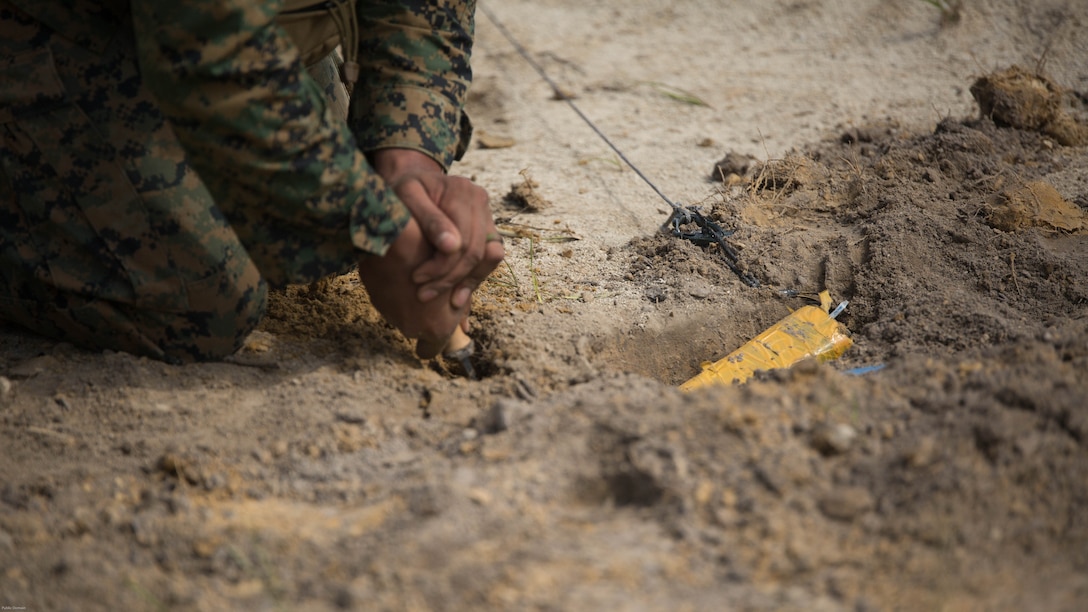 Sgt. Anthony Carbajal, an explosive ordnance disposal team leader with 2nd EOD Company, 8th Engineer Support Battalion, removes dirt surrounding a controlled improvised explosive device during a training exercise at Marine Corps Base Camp Lejeune, N.C., July 19, 2016. The unit conducted the training to test the effects of different types of excavation charges. 