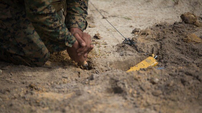 Sgt. Anthony Carbajal, an explosive ordnance disposal team leader with 2nd EOD Company, 8th Engineer Support Battalion, removes dirt surrounding a controlled improvised explosive device during a training exercise at Marine Corps Base Camp Lejeune, N.C., July 19, 2016. The unit conducted the training to test the effects of different types of excavation charges. 